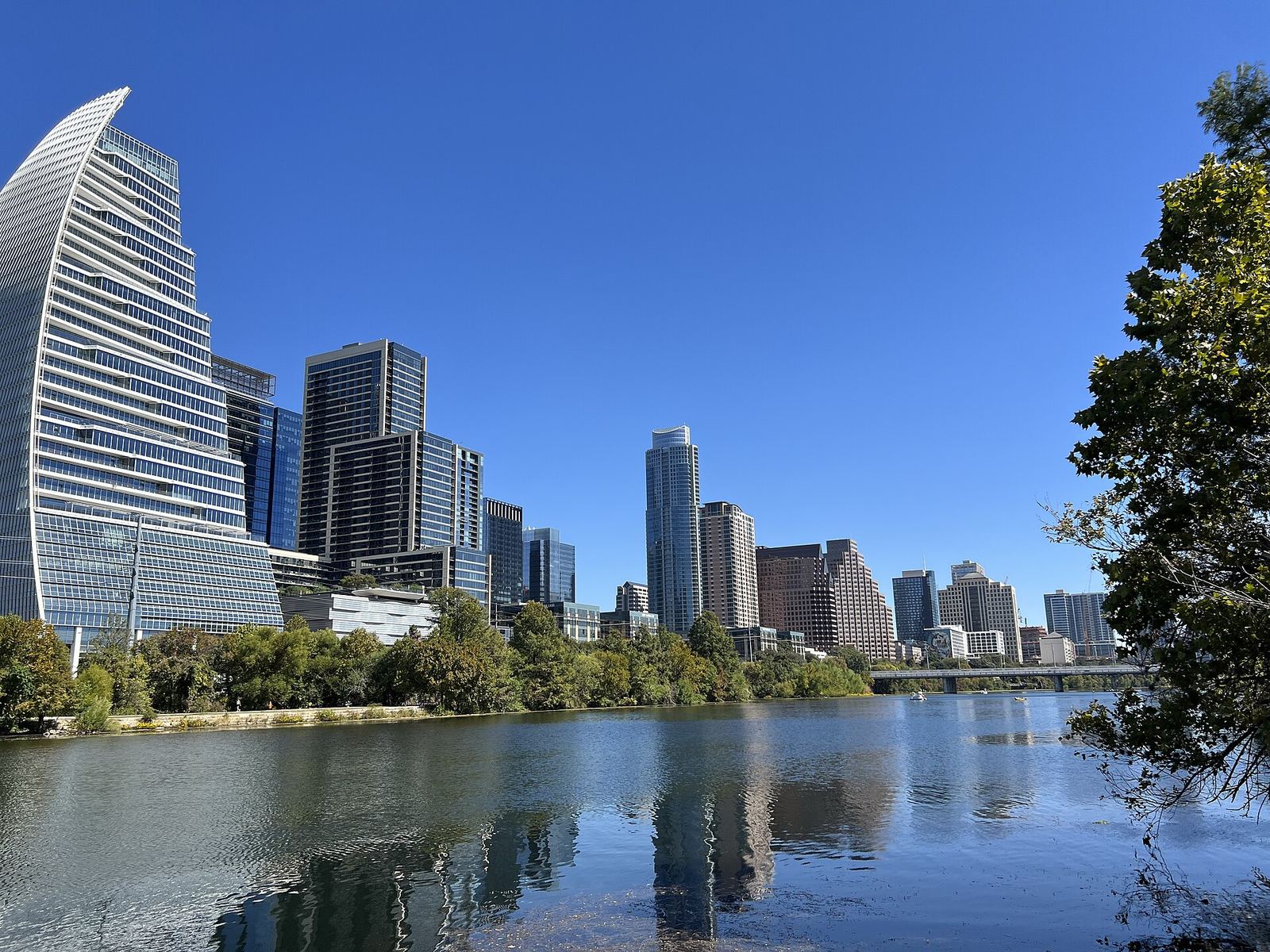 Lady Bird Lake reflecting the downtown Austin skyline, with trees along the shore