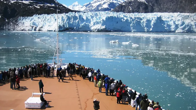 Passengers on a cruise ship bow facing a tidewater glacier in Glacier Bay National Park, Alaska