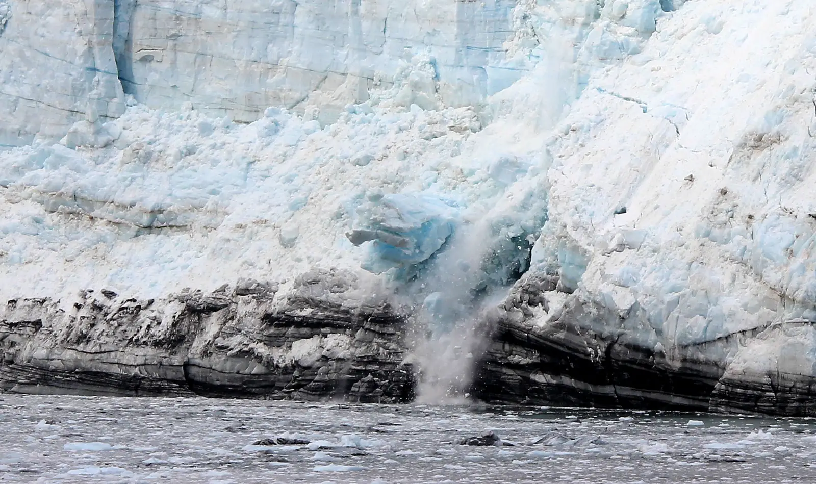 Ice calving from the face of Margerie Glacier into the water in Glacier Bay, Alaska