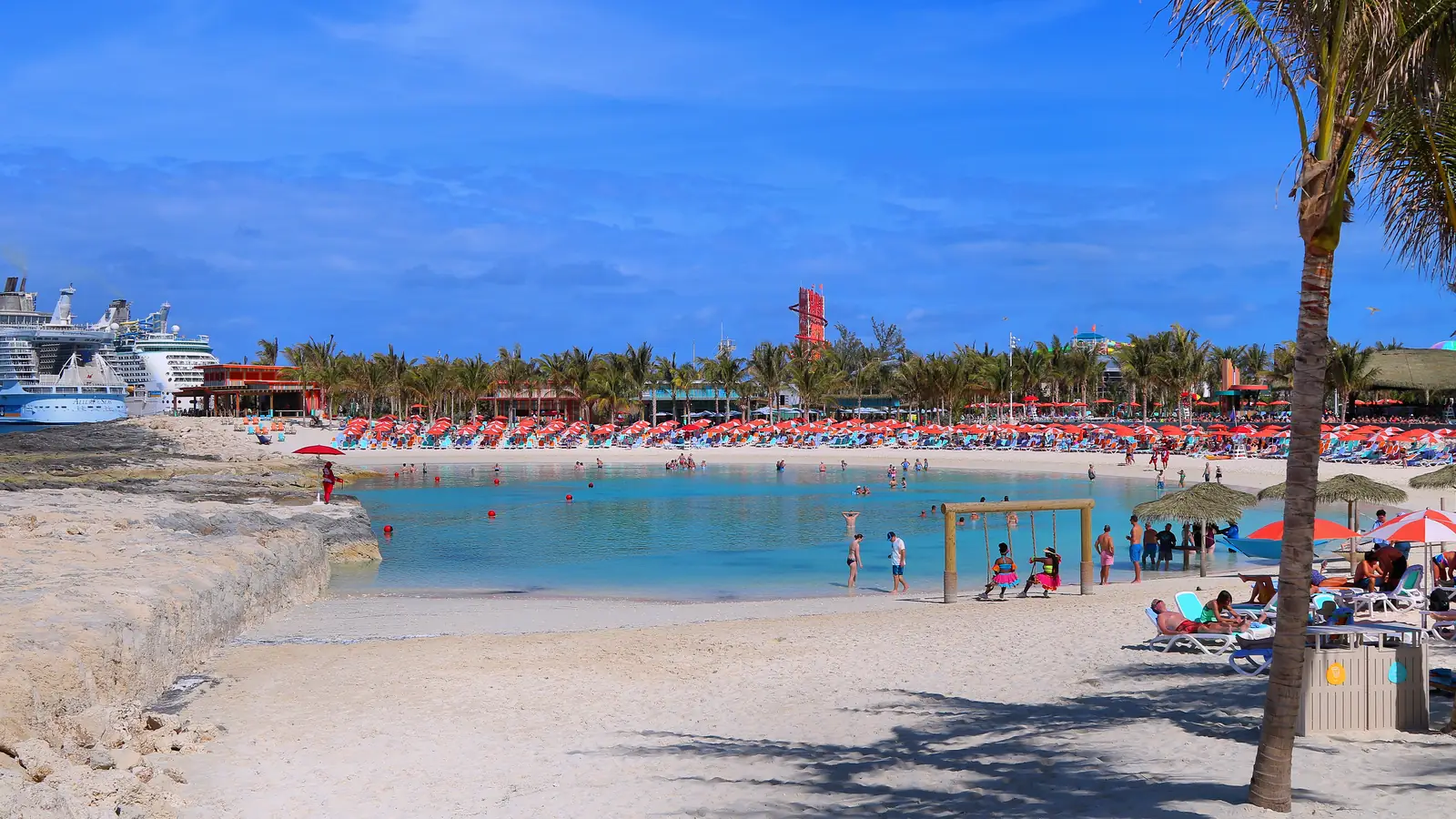 Beach with loungers and palm trees beside calm water on a Bahamas island