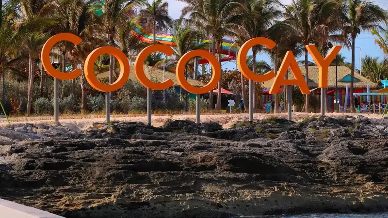Large orange letters spelling the island's name on rocks above the sea in The Bahamas