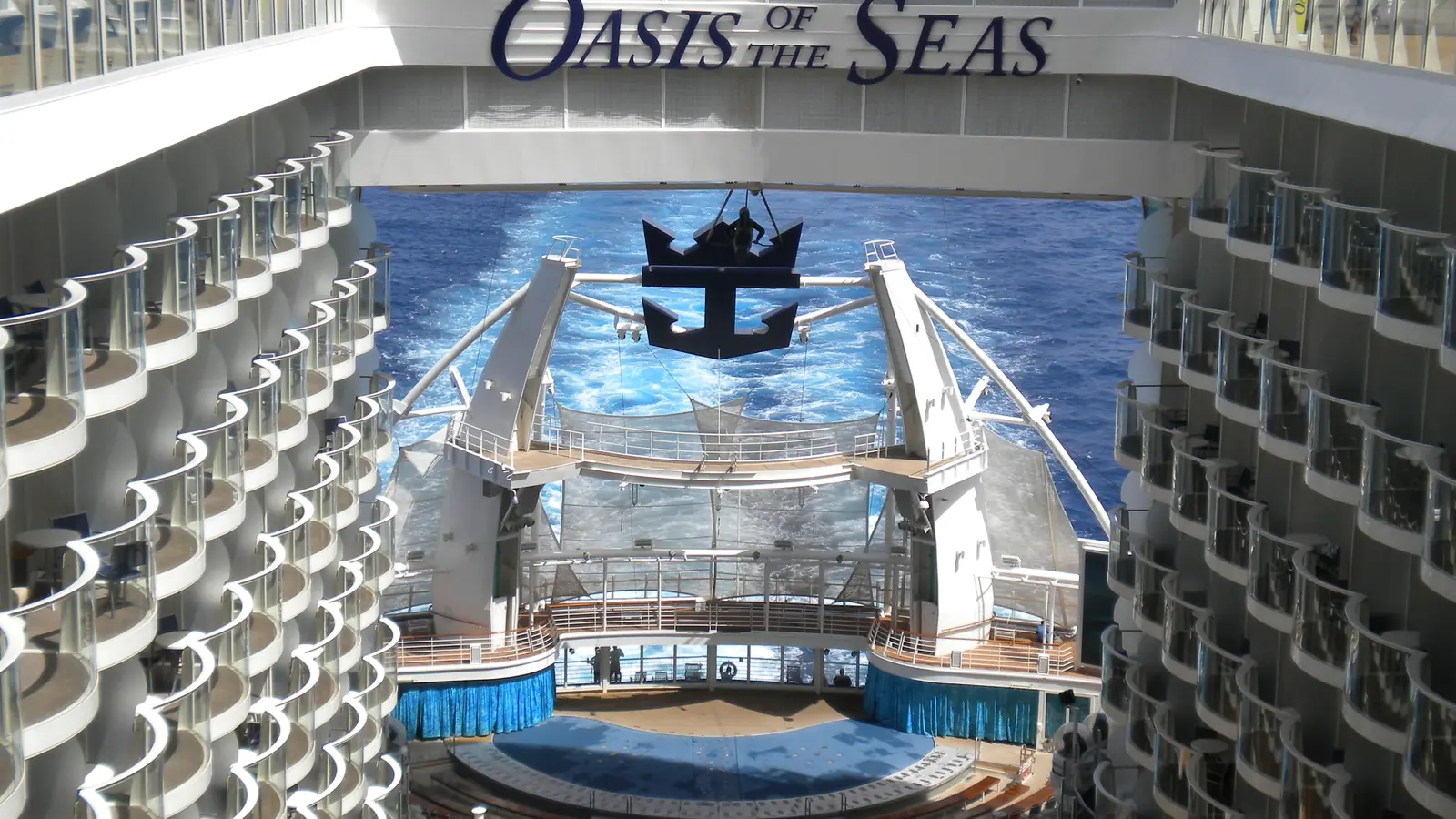 An outdoor aqua theater at the stern of a big family cruise ship, seen from the boardwalk, with the ship's wake behind it