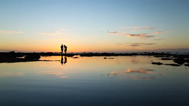 Silhouette of a couple on the shore against a golden ocean sunset
