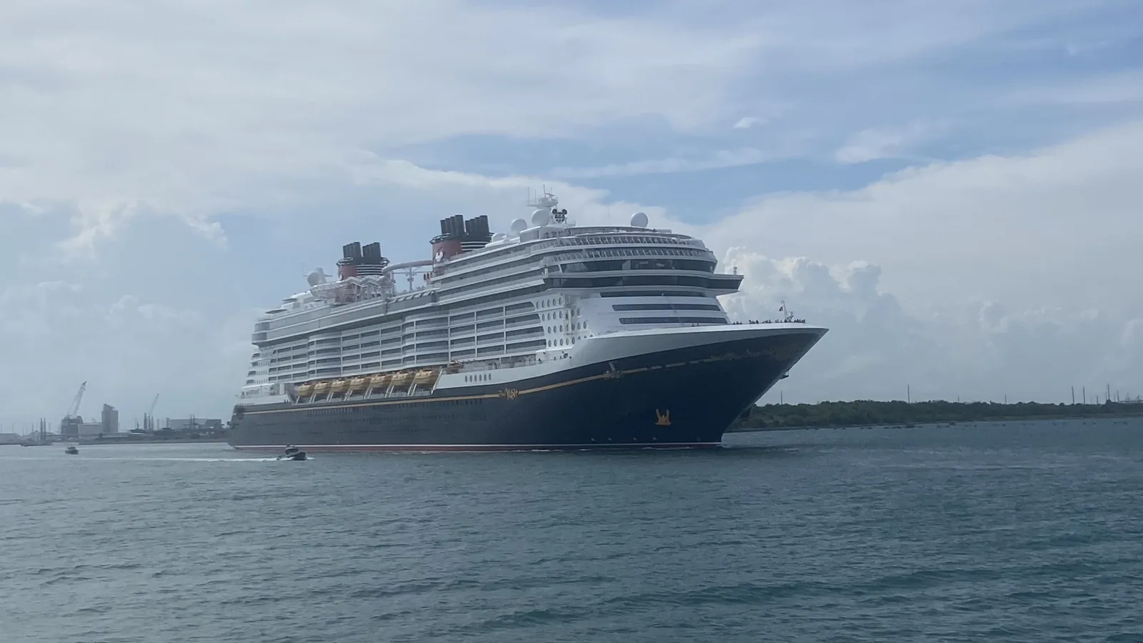 Large cruise ship sailing out of Port Canaveral, Florida, under a cloudy sky