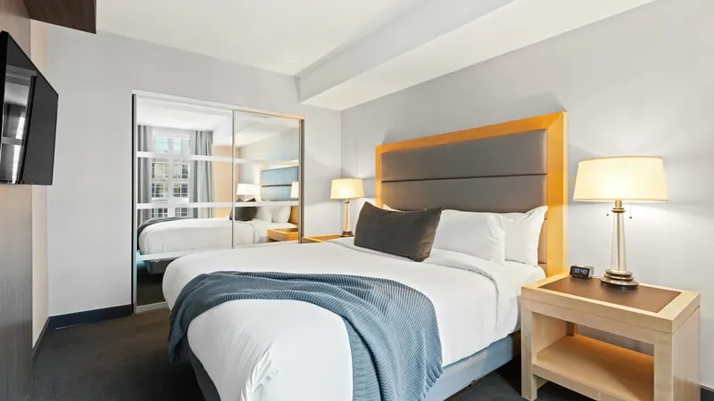 Hotel room with a made bed, padded headboard and bedside lamp