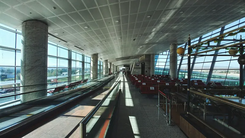 Long, sunlit airport concourse with a moving walkway and rows of seats
