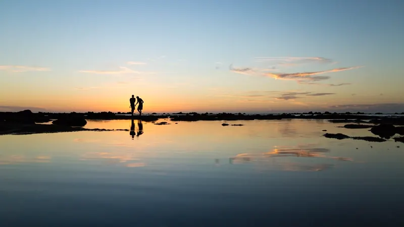 Silhouette of a couple on the shore against a golden ocean sunset