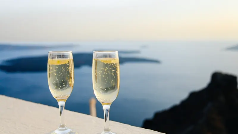 Two glasses of bubbly on a sunny ledge with the sea and cliffs behind