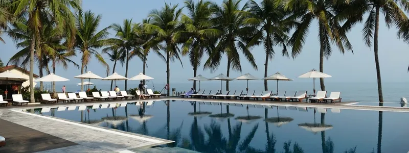 Resort swimming pool lined with palm trees and loungers under a blue sky