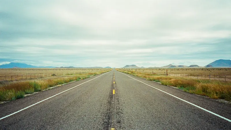 Open two-lane highway across flat grassland under a wide sky