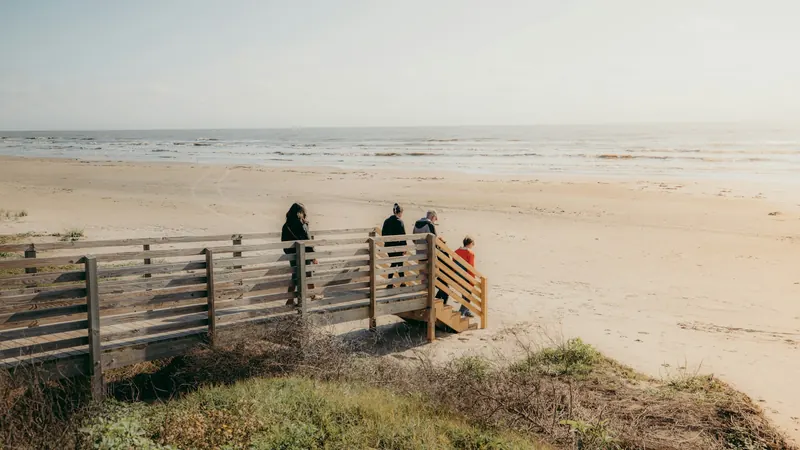 Wooden boardwalk over grassy dunes beside a wide Gulf beach