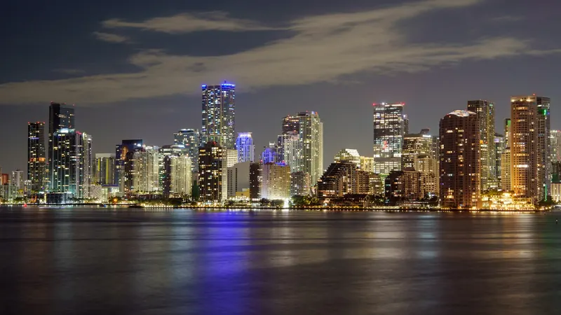 Miami skyline lit up at night and reflected in the bay