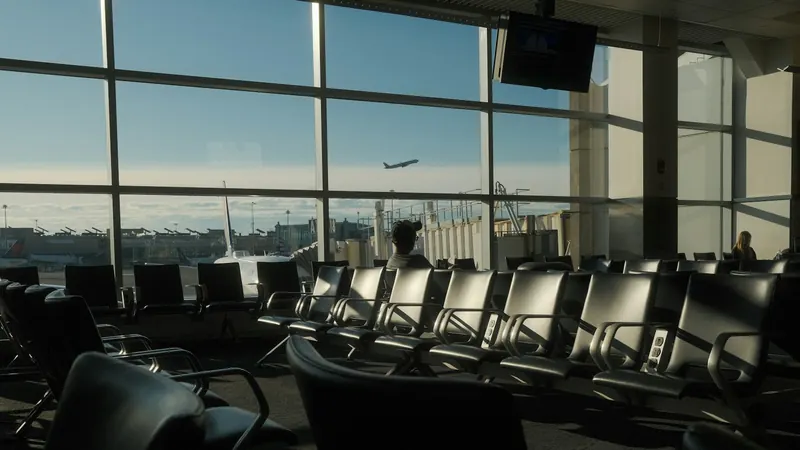Rows of seats at an airport gate, with a plane taking off outside