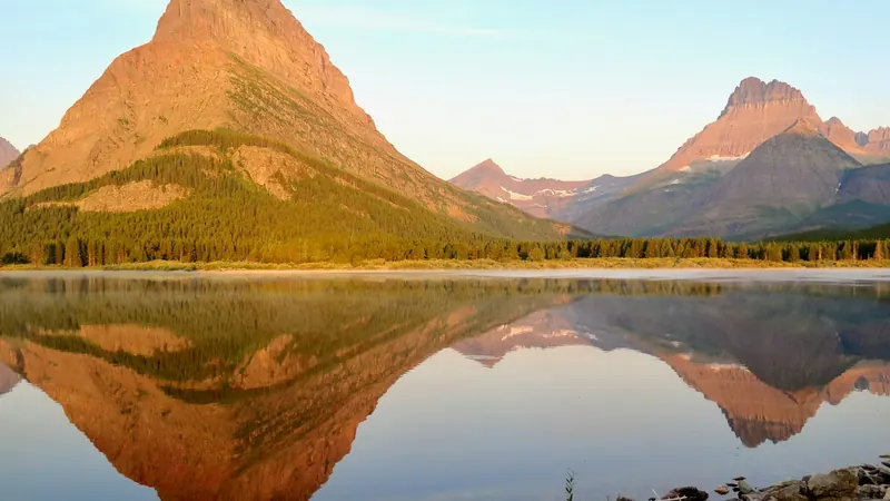 Mountain peaks reflected in a still lake under a clear sky
