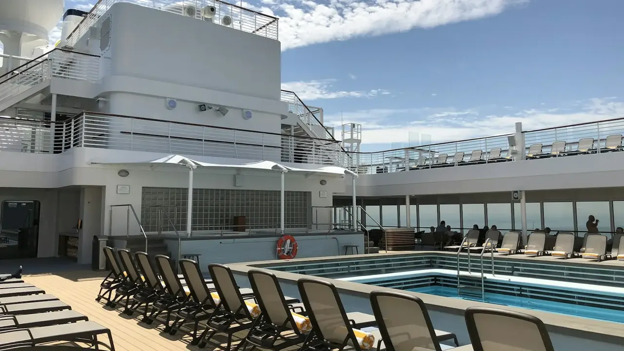 Rows of loungers around a sunny pool on a cruise ship deck