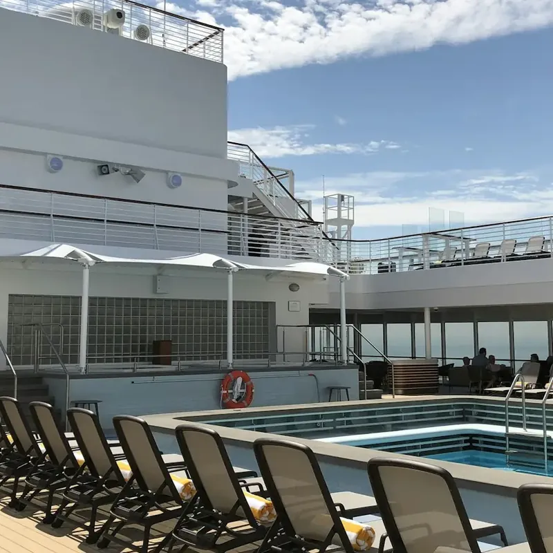 Rows of loungers around a sunny pool on a cruise ship deck